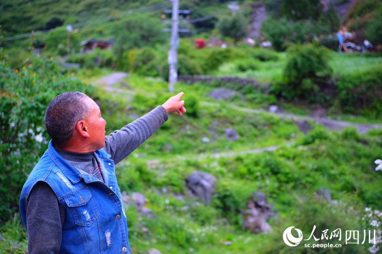 然拉木滾指著自己已經被掩埋的房子。陳瀟洋攝