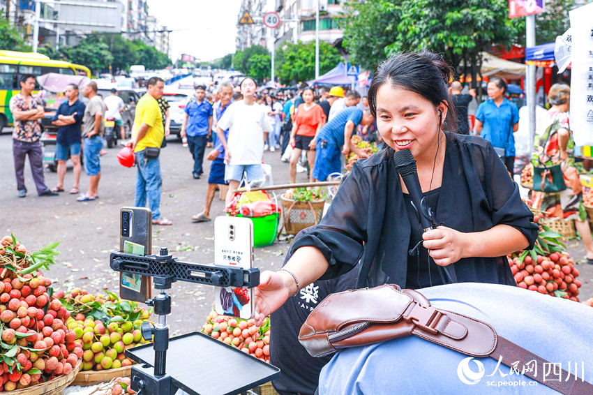合江縣馬街荔枝交易市場上，來自符陽街道三塊石村的胡麗在自己的荔枝銷售攤點上進行現場直播售貨。李貴平攝