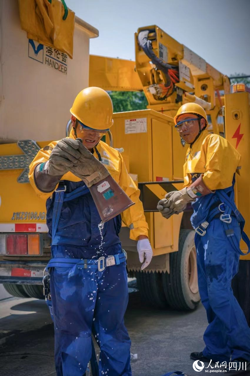 國網眉山供電公司帶電作業人員開展帶電作業后，傾倒絕緣手套，汗如雨下。茍華彬攝