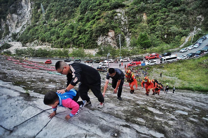 9月5日，消防救援人員因山體滑坡、道路中斷，通過攀爬挺進磨西鎮。四川省消防救援總隊供圖