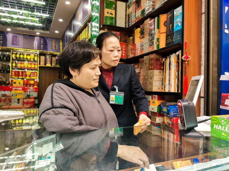 客戶經理鄭向紅向喻明珠妻子講授使用智慧收銀機技巧。受訪者供圖