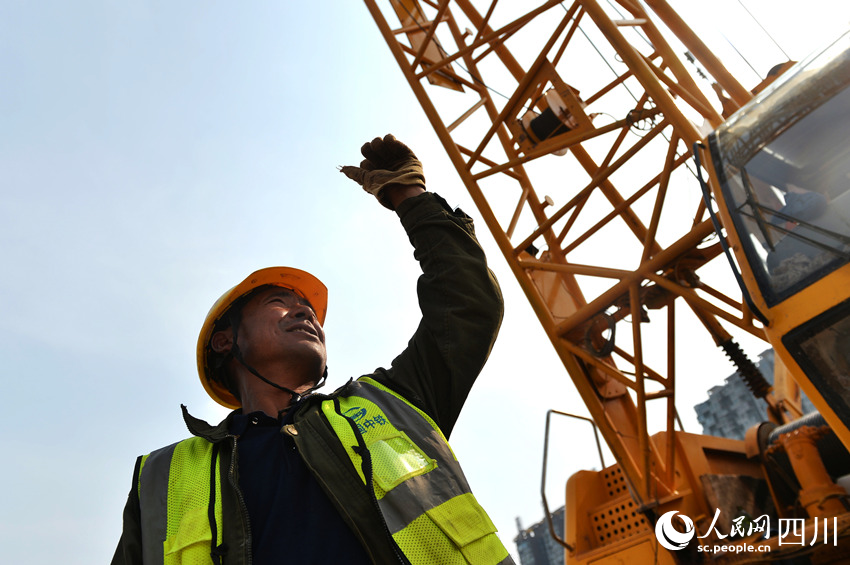 工人在指揮鋼材吊裝。王斌攝