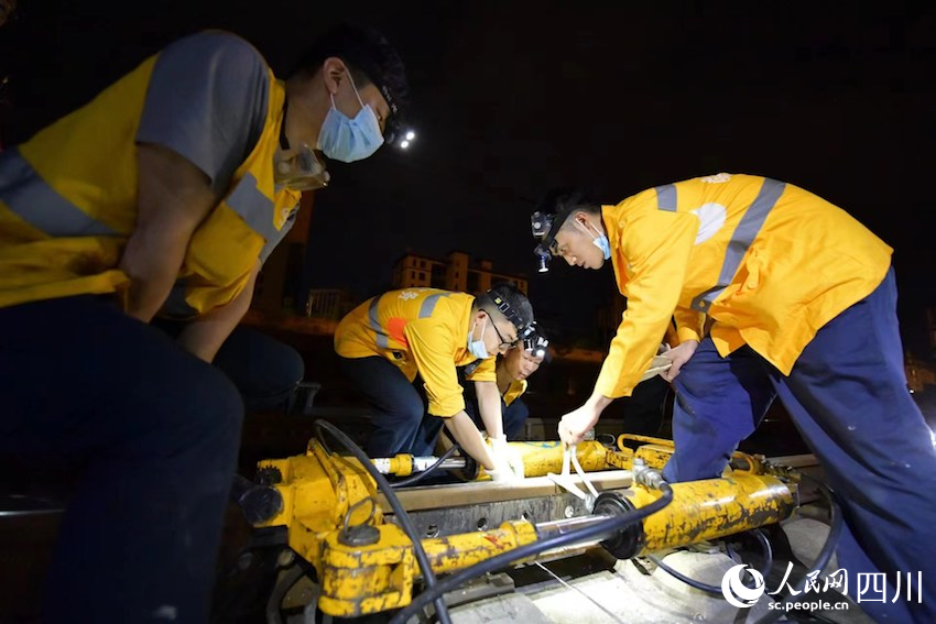 線路工人使用拉伸器對鋼軌焊縫進行拉伸校準。顧銀鋒攝