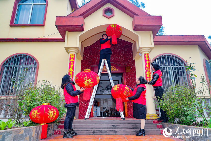 黨員志愿者們為當地村民掛燈籠、貼春聯。牟科攝
