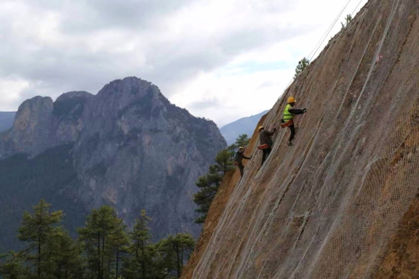 工人們綁著安全繩，在絕壁懸崖上“摳”出炮眼。四川省交通運輸廳供圖