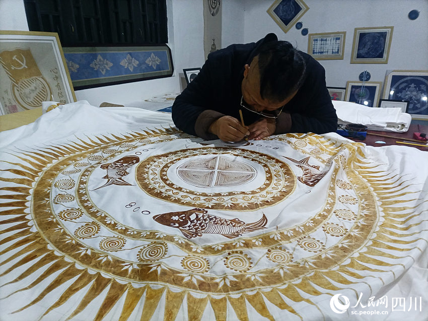 楊安平在蠟布上刻畫圖案。曾剛攝