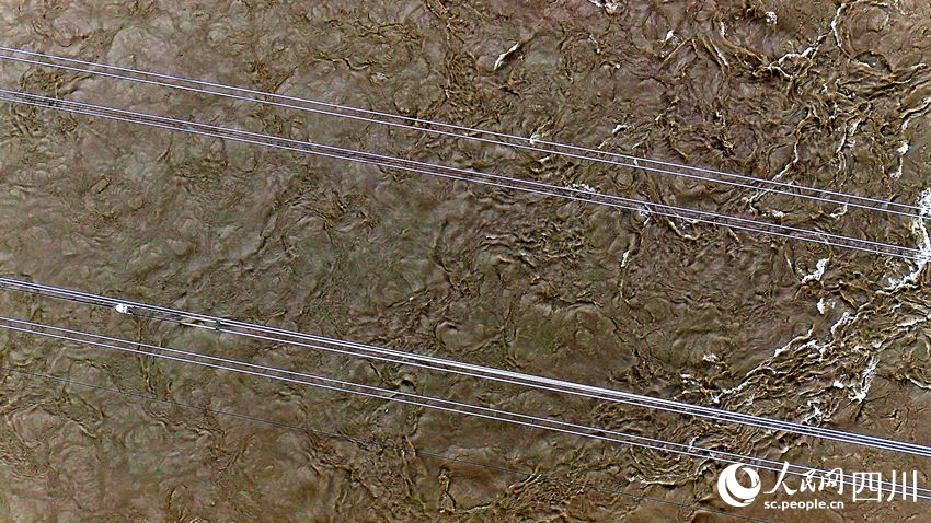 輸電導線正在被牽引跨越波濤洶涌的大渡河。劉湘釩攝