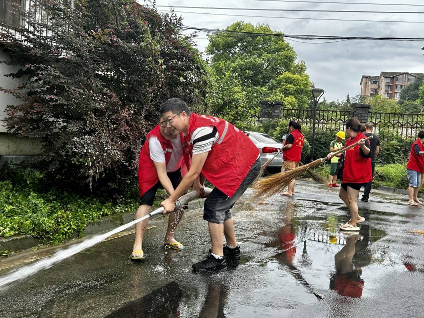 程平（左二）與社區工作人員一同清理小區淤泥。都江堰市融媒體中心供圖