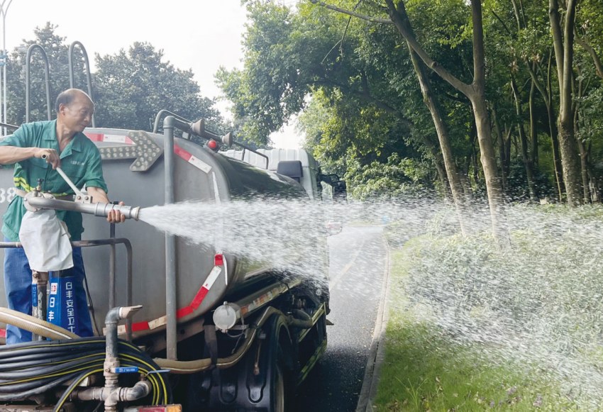 綠化工人站在灑水車上澆灌綠植。曾剛攝