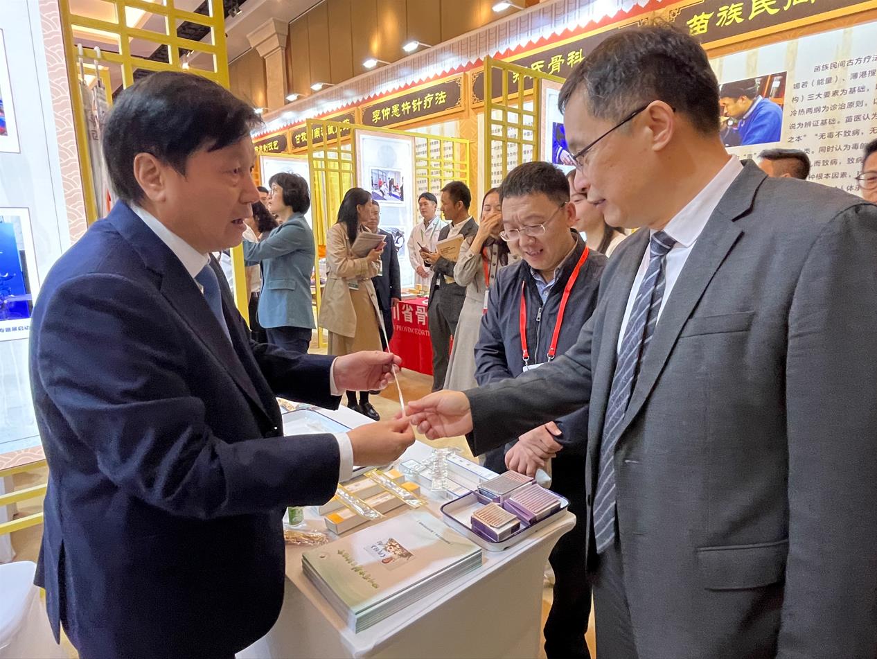 中醫藥展覽展示大會上，唐德厚（左）向國家中醫藥管理局副局長黃璐琦（右）介紹“唐氏芒針”。受訪者供圖