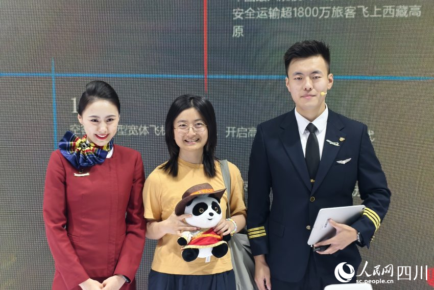 參與互動的參展觀眾在領取禮物后同中國國際航空公司展館工作人員合影。人民網 趙祖樂攝