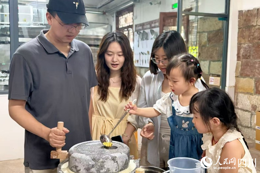 參加研學的孩子在家長的陪同下，上手體驗先市醬油制作（部分環節）。楊藺攝