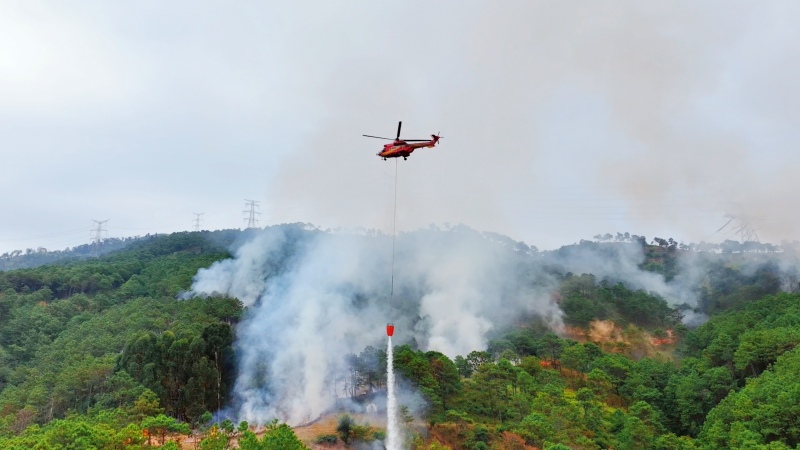 直升機掛載吊桶精準噴灑關鍵火點。李威攝