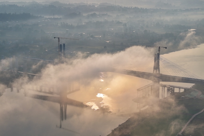 晨曦微露，大橋橫跨江面，隱于薄霧，美不勝收。成達萬高速鐵路有限責任公司供圖